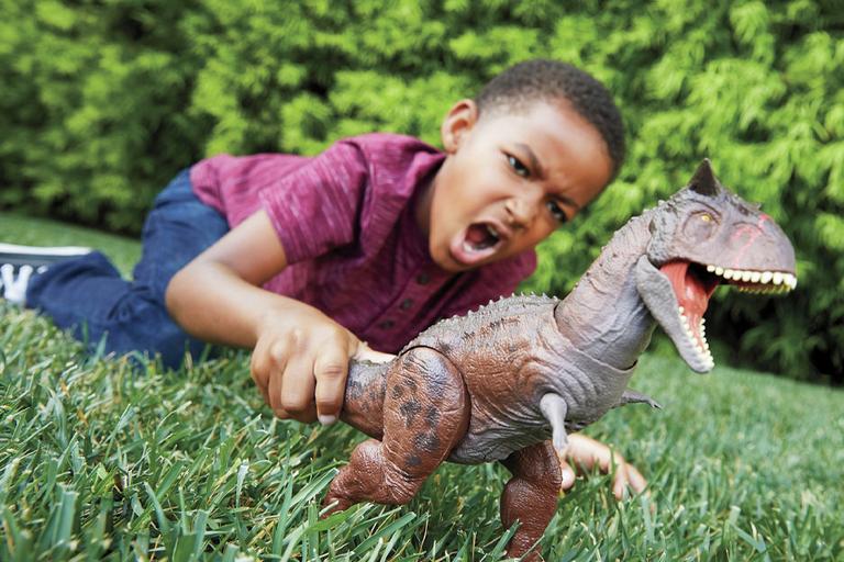 Boy playing with Jurassic World Control 'N Conquer Carnotaurus Toro in the garden.