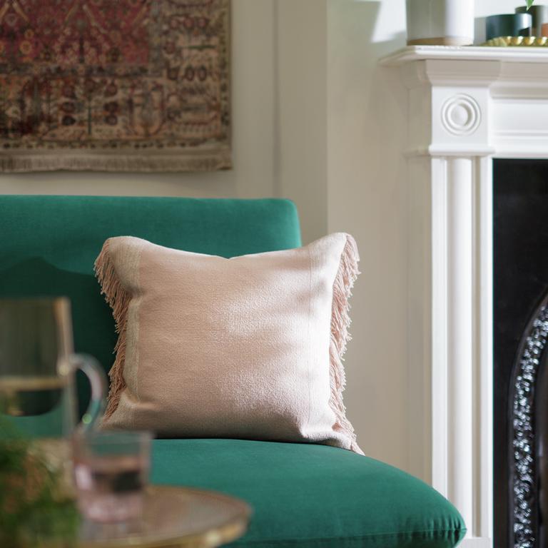 Image of a cream velvet cushion on a turquoise chair.