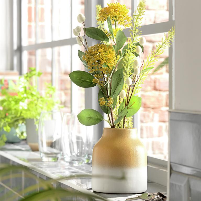 Image of a yellow and white vase with a yellow artificial plant in it.