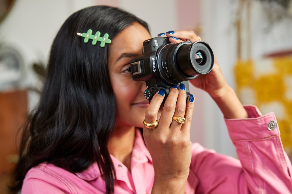 A woman taking photographs with a Canon EOS R series mirrorless camera. 