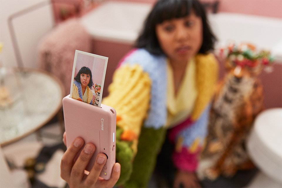 A woman taking a photograph with a portable Canon Zoemini S2 instant camera printer. 