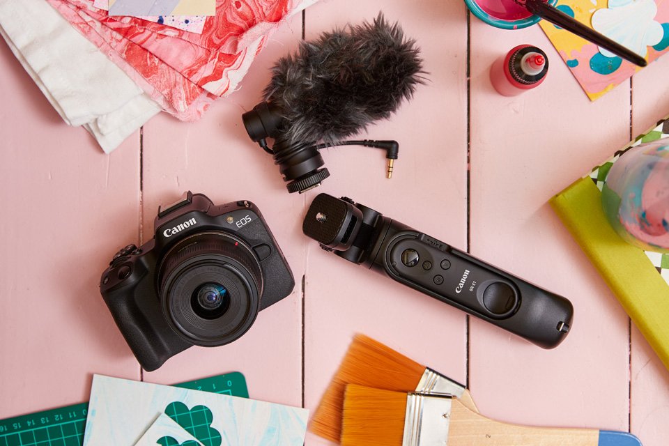 A Canon EOS R50 creator kit placed on a pink art studio table. 