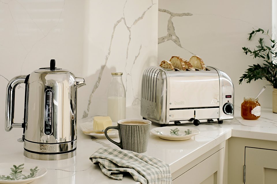 A Dualit Classic kettle and a Classic toaster with other things on a white kitchen counter. 