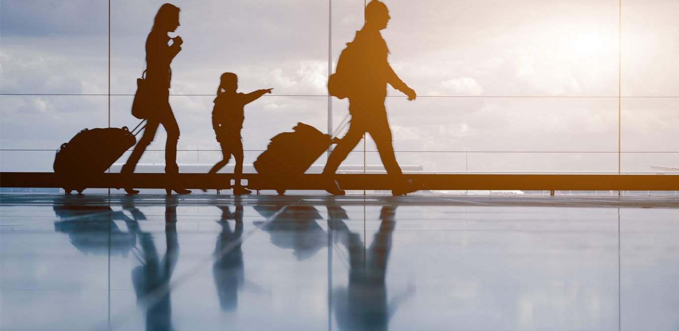 People walking through an airport with different coloured suitcases and backpacks.