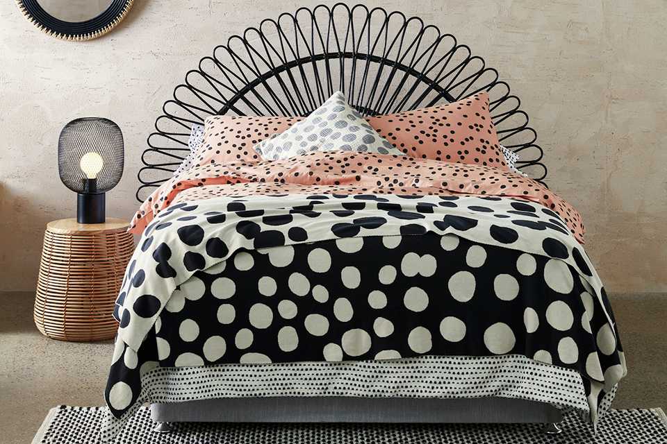 Black rattan headboard on bed with polka dot bedding 