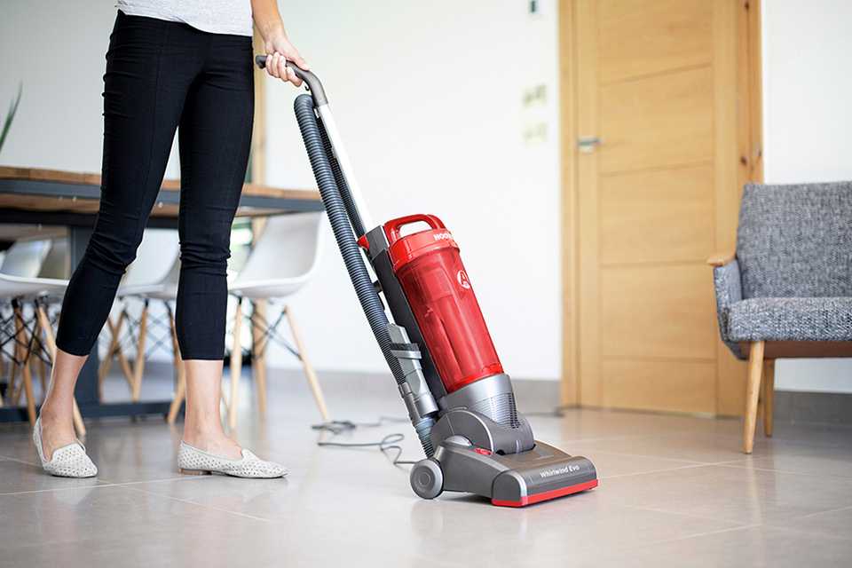 A lady vacuuming the floor with the Hoover WRE06 Whirlwind Evo Upright vacuum cleaner.