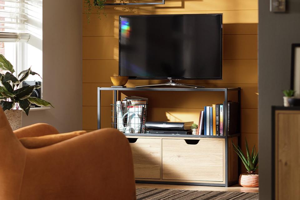 A black framed, wooden finish TV unit in a yellow living room.