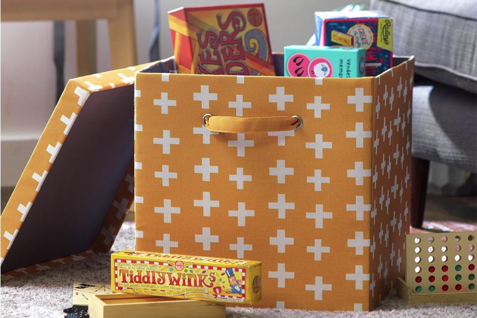 An orange decorative toy storage box with a white cross pattern on it.