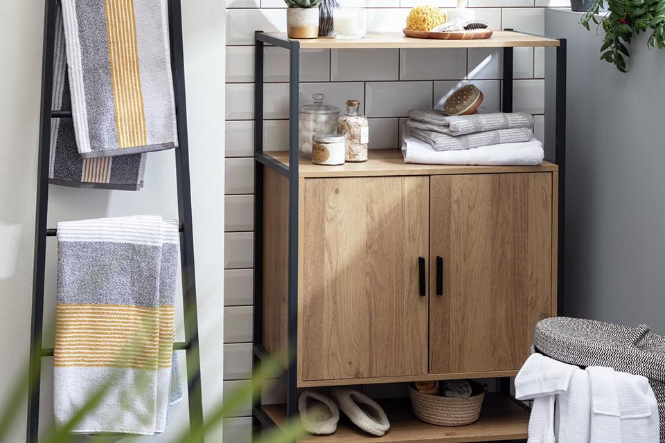 A natural finish undersink storage with a black frame displying bathroom accessories.