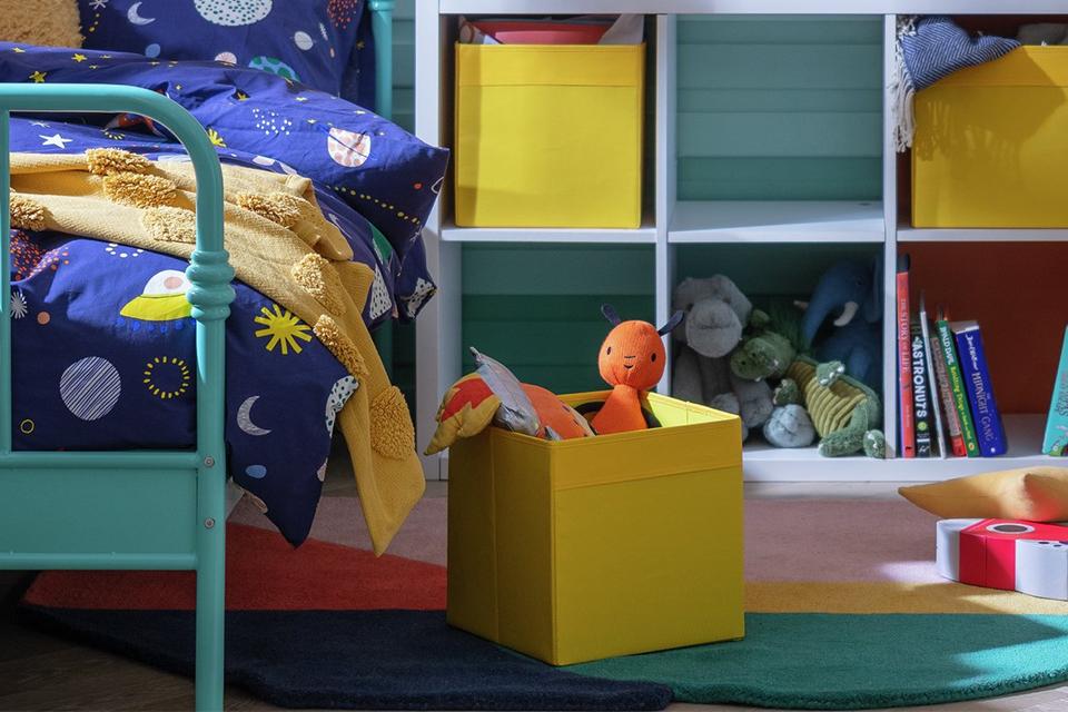 A set of 4 yellow canvas boxes in a white cube storage shelf displayed in a kid's room.