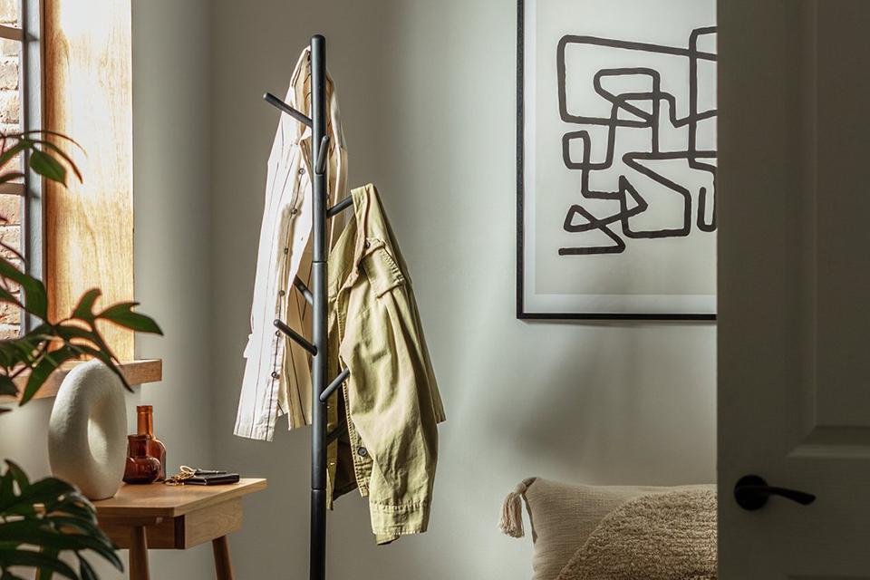 A Habitat coat tree stand in black with a shirt and a jacket hanging on it.