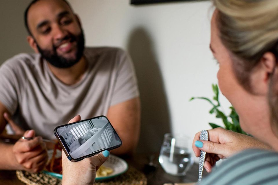 A mother keeping an eye on her baby through Tommee Tippee Dreamsense baby monitor app on her phone.