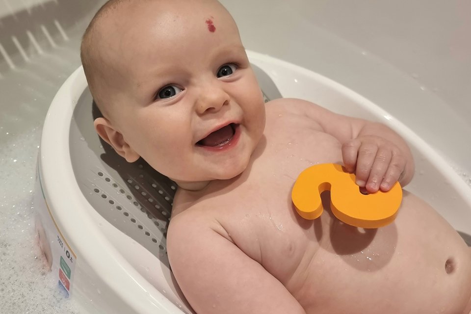 A baby taking bath with Nuby bath support. 