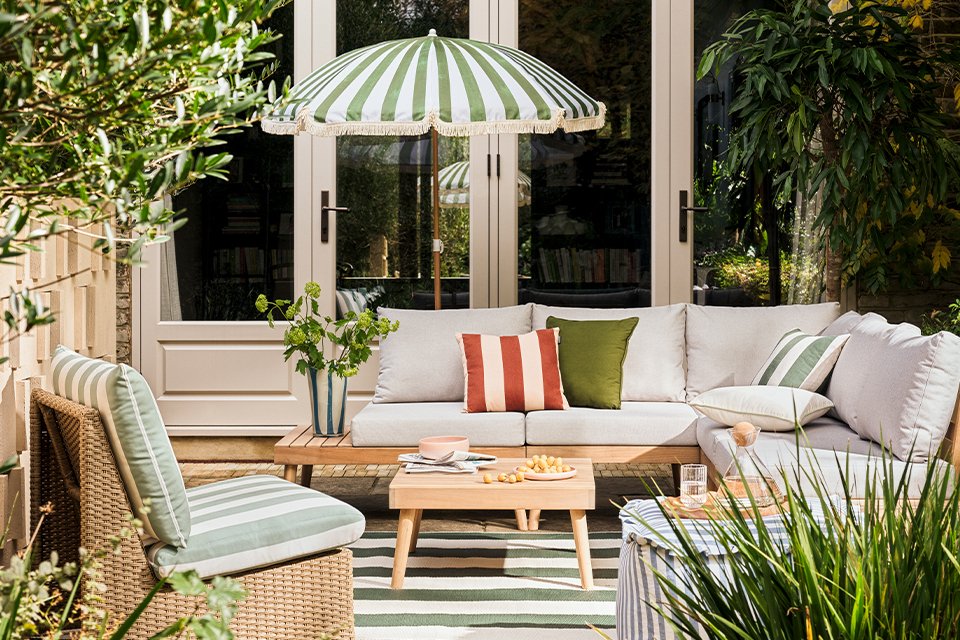 Habitat Wooden Garden Sofa Set places outdoors with stripes cushions on it and a wooden coffee table in front of it.