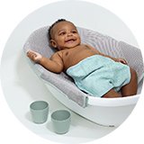 A baby in an Ingenuity 4 in 1 Room To Soak Tub Baby Bath.