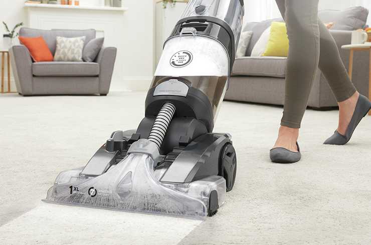 Woman using a carpet cleaner on a living room carpet.