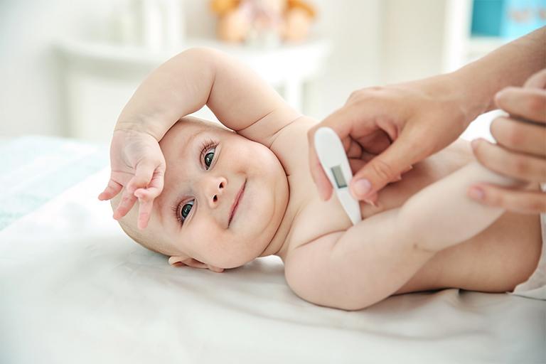 A woman using a digital thermometre on a baby.