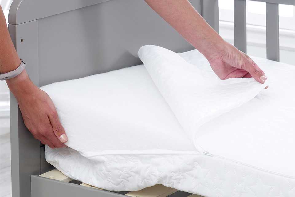 A person checking the white mattress cover.