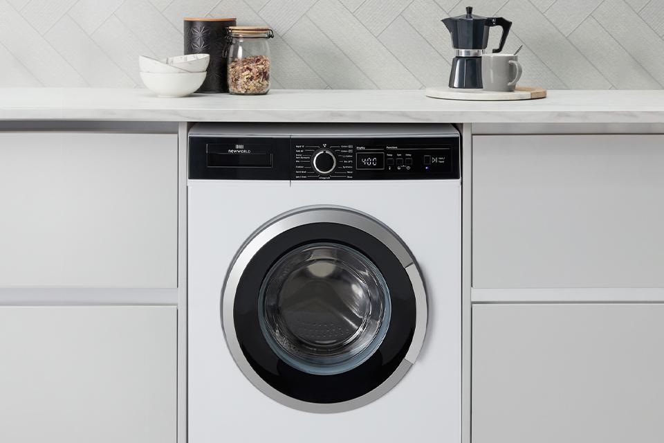 A white washing machine in a white, fitted kitchen.