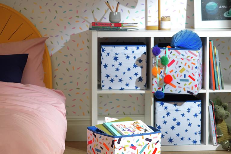 Multi-coloured canvas toy boxes on a white cube storage shelf in a kid's room.
