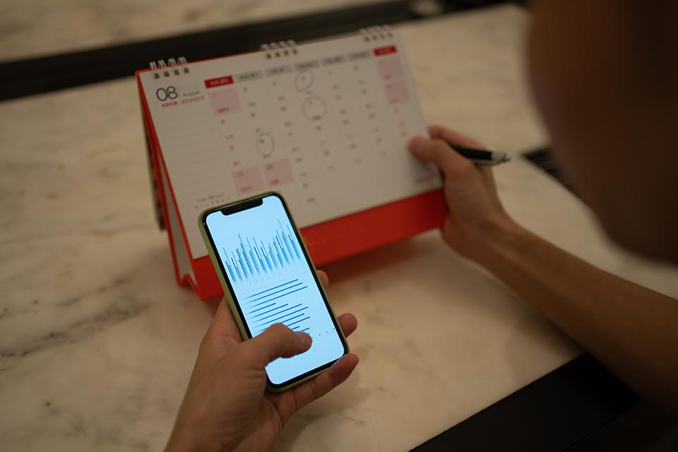 A customer holding a mobile phone checks a calendar.