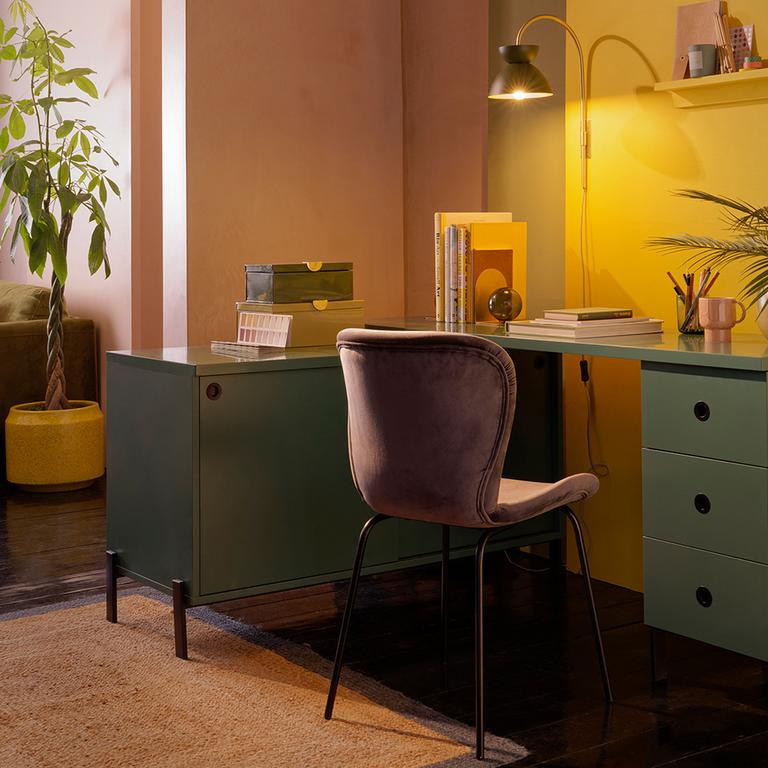 A 3 drawer swivel desk in green with a pink velvet chair. 