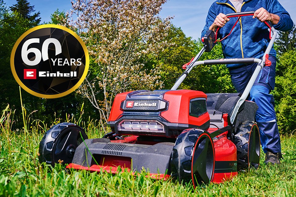 A man using an Einhell cordless lawn mower against a fresh patch of grass.
