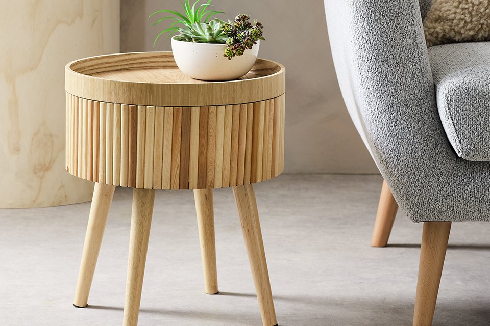 A Habitat natural round side table placed next to a sofa.