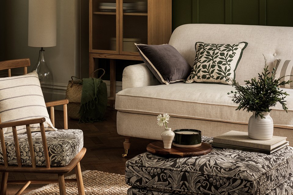 A Habitat x Morris & Co. white Oak Armchair next to a wooden bookcase in a room.