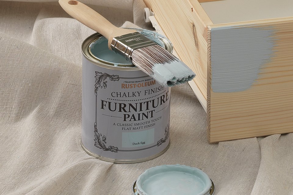 A paint brush on a can of furniture paint.