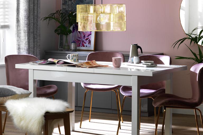 Pedestal dining table with pink upholstered chairs.