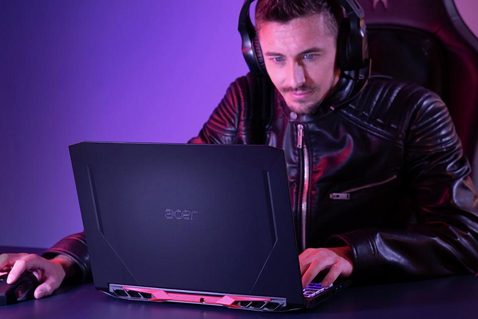 A man using an Acer Nitro 5 gaming laptop with gaming headphones on.