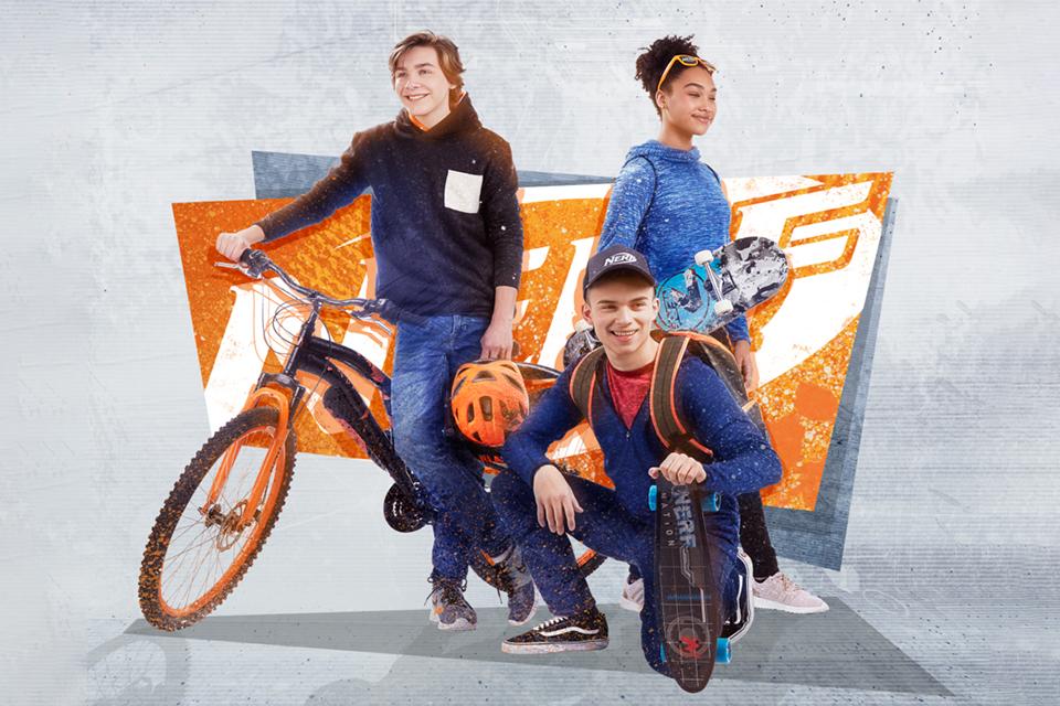 Two boys and a girl with skateboards and a bike.
