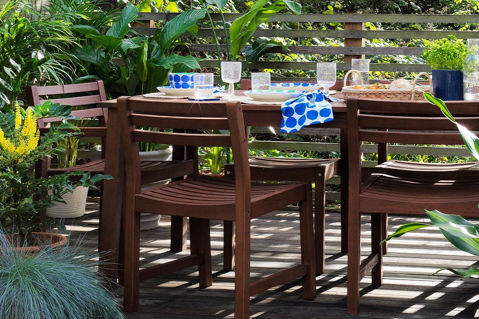 An outdoor amalfi six seater patio set in a wooden brown with spring tableware.