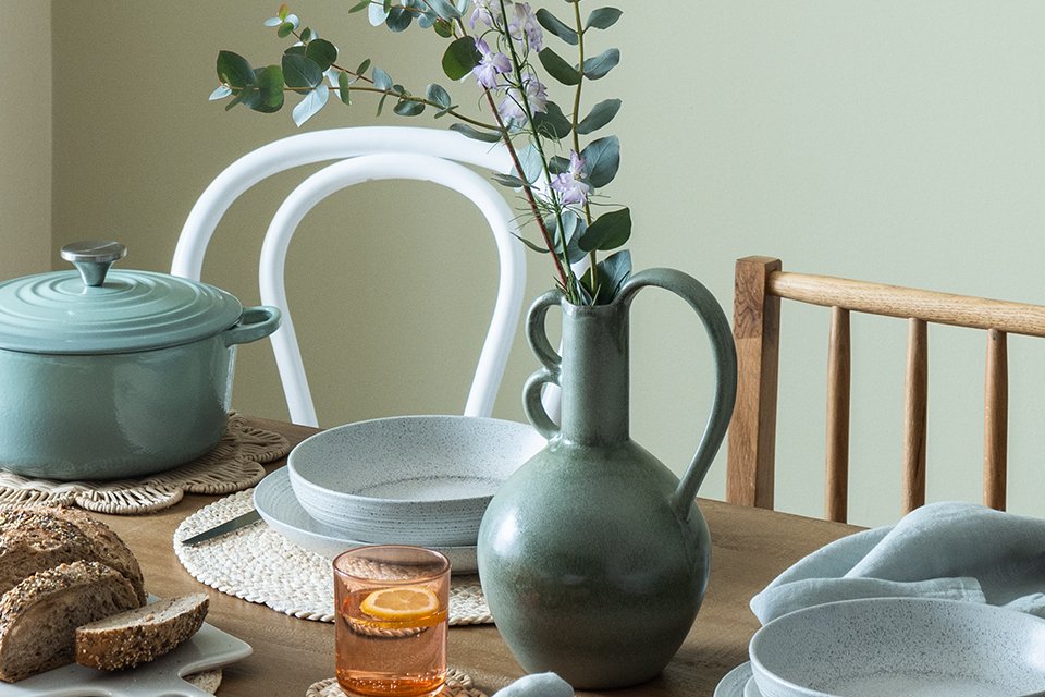 A dark green vase kept on a dining table.