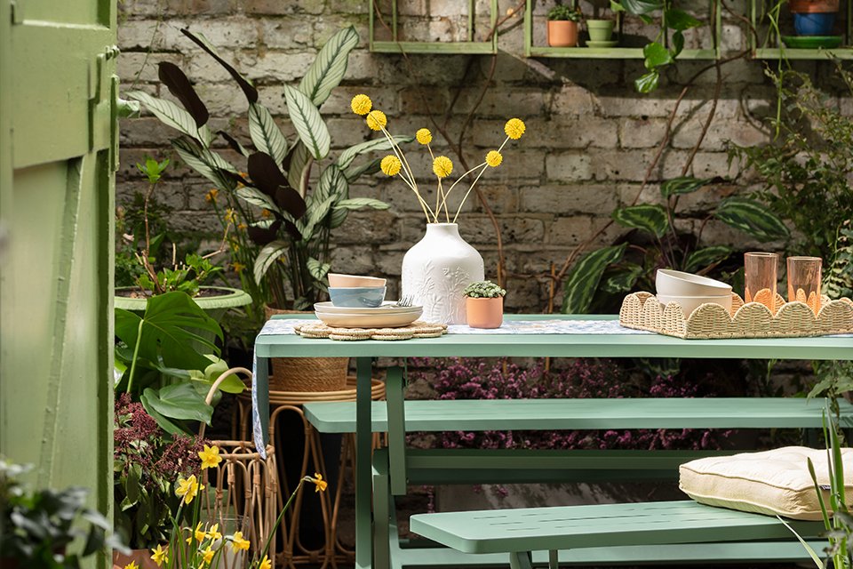 A green dining table and benches sitting in an outdoor area.