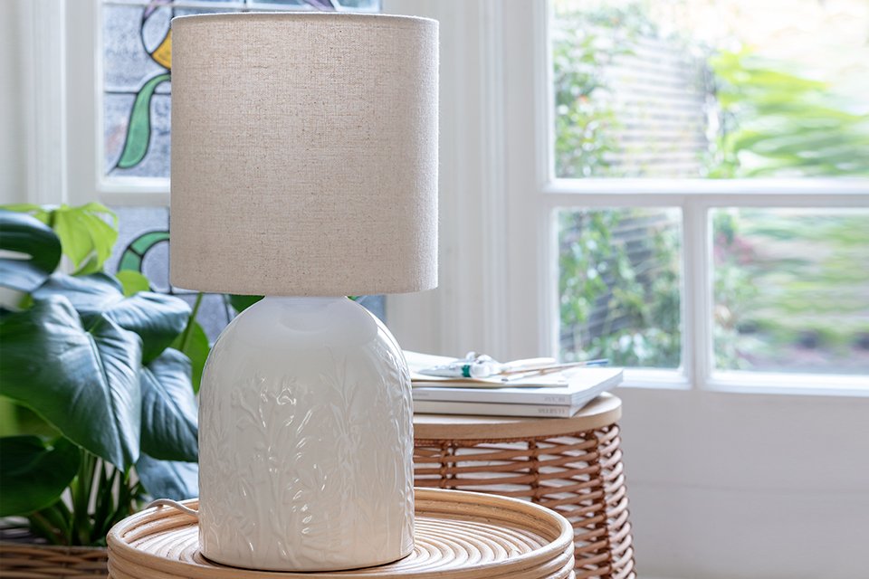 A white table lamp with a cream lamp shade.