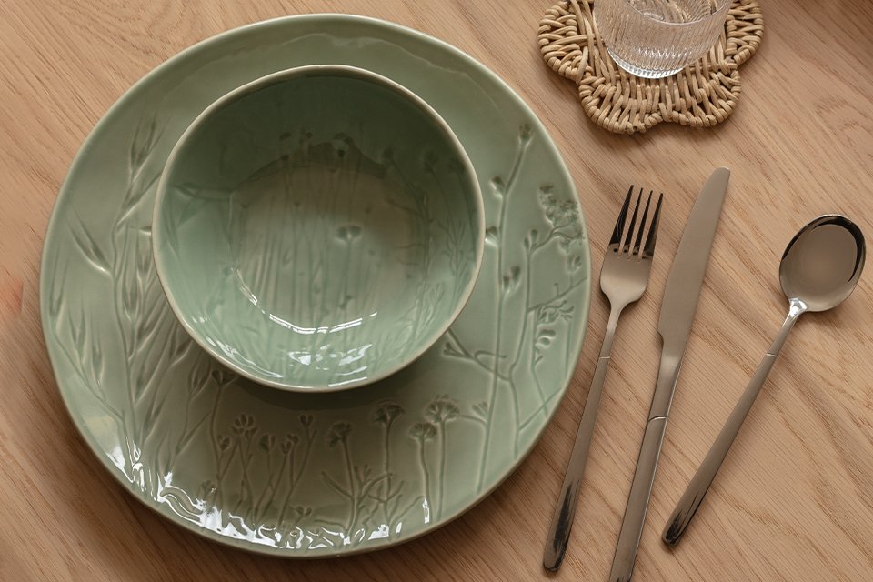 An olive green cup and saucer kept on a table.