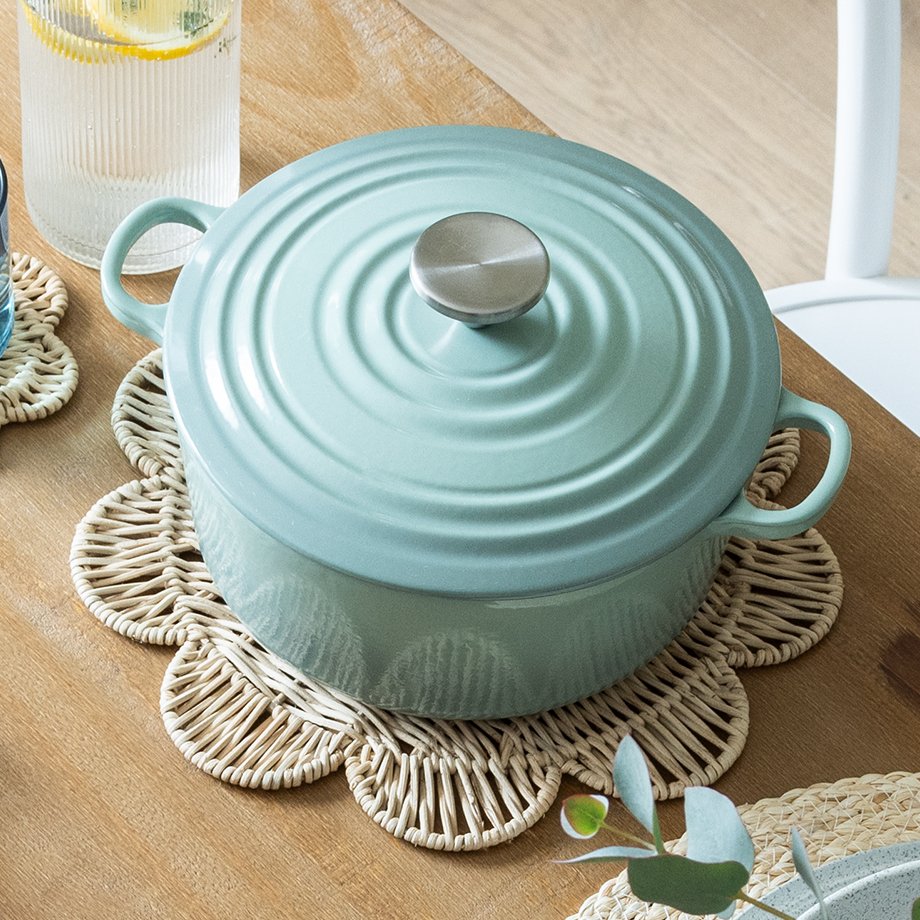 A fresh summer dining room table set up with wicker scalloped placemat and blue oval iron cast casseole dish.