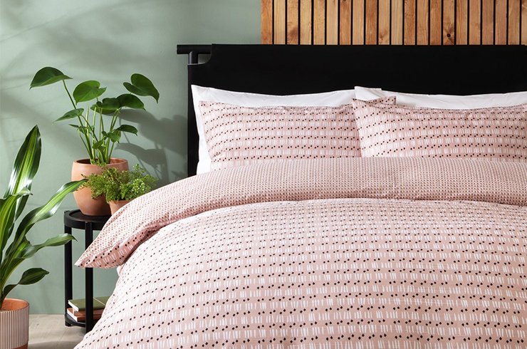 Double bed with pink patterened bedding in green bedroom.