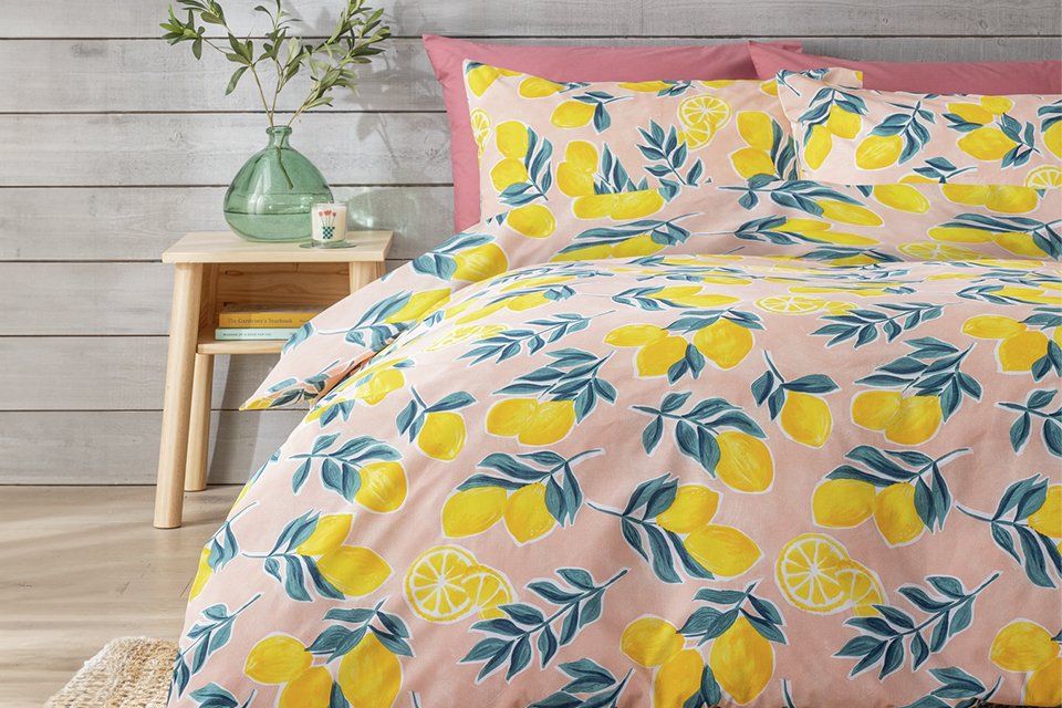 pink bedding set with lemon print design on a made bed