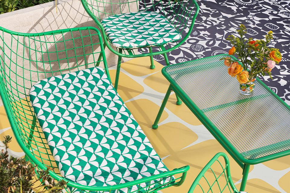 Green garden sofa and chairs with patterned green and white cushions.