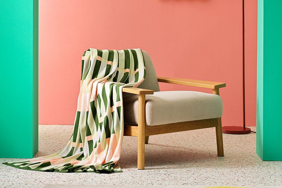 Wooden accent chair with white cushion seat and green and pink printed throw overchair arm.