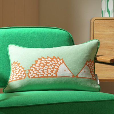 Green cushion with orange printed hedgehogs.
