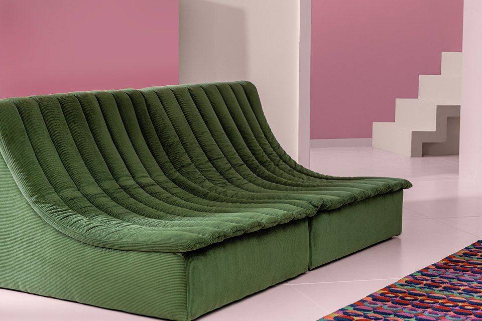 A Habitat scoop chair in green next to a colourful rug.