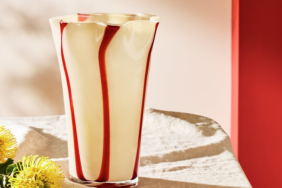 Cream glass vase with red stripes.