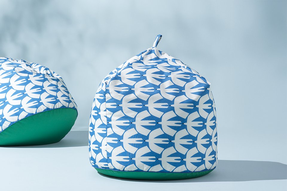 Outdoor Scion x Habitat colelction bean bag with yellow and white strips with leaopard print layered over stripes, in a garden corner next to planters perfect for an outdoor reading spot.