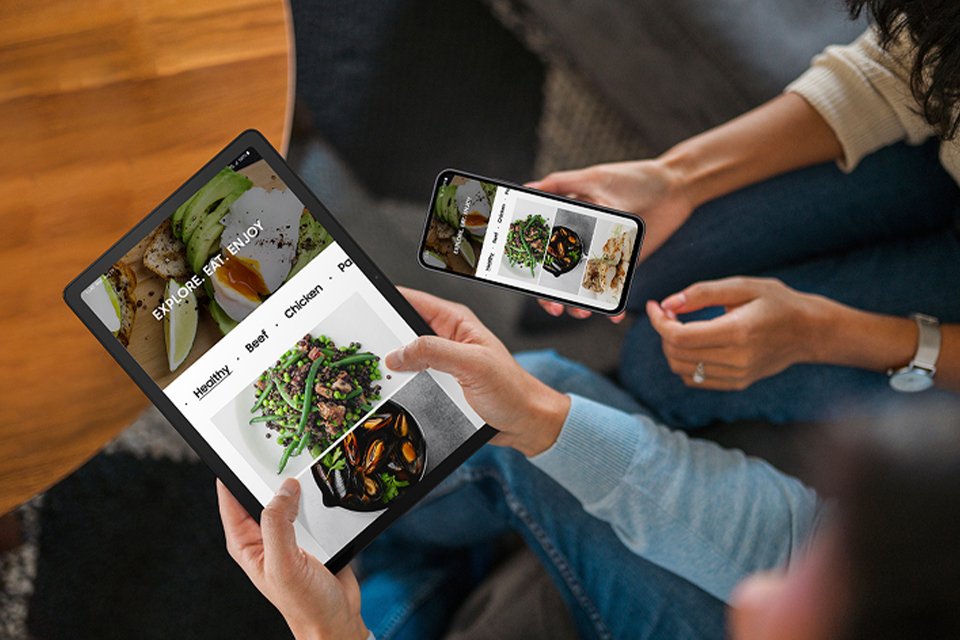 Two people holding Samsung Galaxy tablet and a Samsung mobile phone side by side.