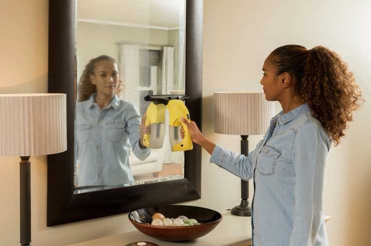 Woman cleaning a mirror with a glass cleaner.