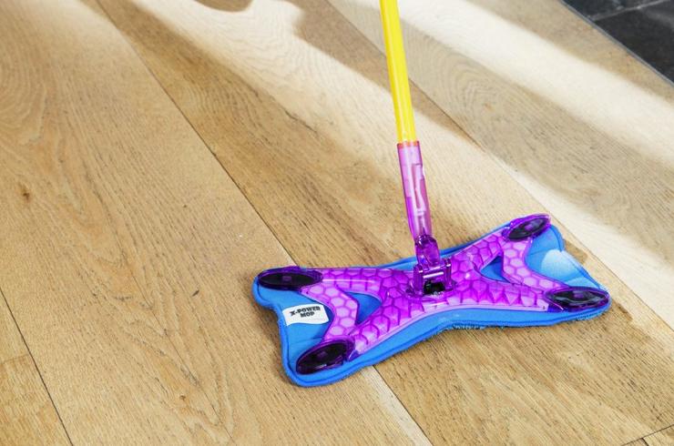 A microfibre mop being used to clean laminate flooring.